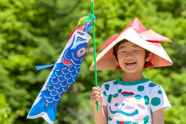 Imagem mostra um menino com uma flâmula de carpa, em alusão ao Dia da Criança no Japão, que se celebra em duas datas diferentes ça pelo mundo